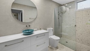 A modern bathroom with a round mirror, a blue basin, a toilet, and a glass-enclosed shower. - Maddlyn with  Ocean Views & Peaceful Treed Retreat (Lorne)