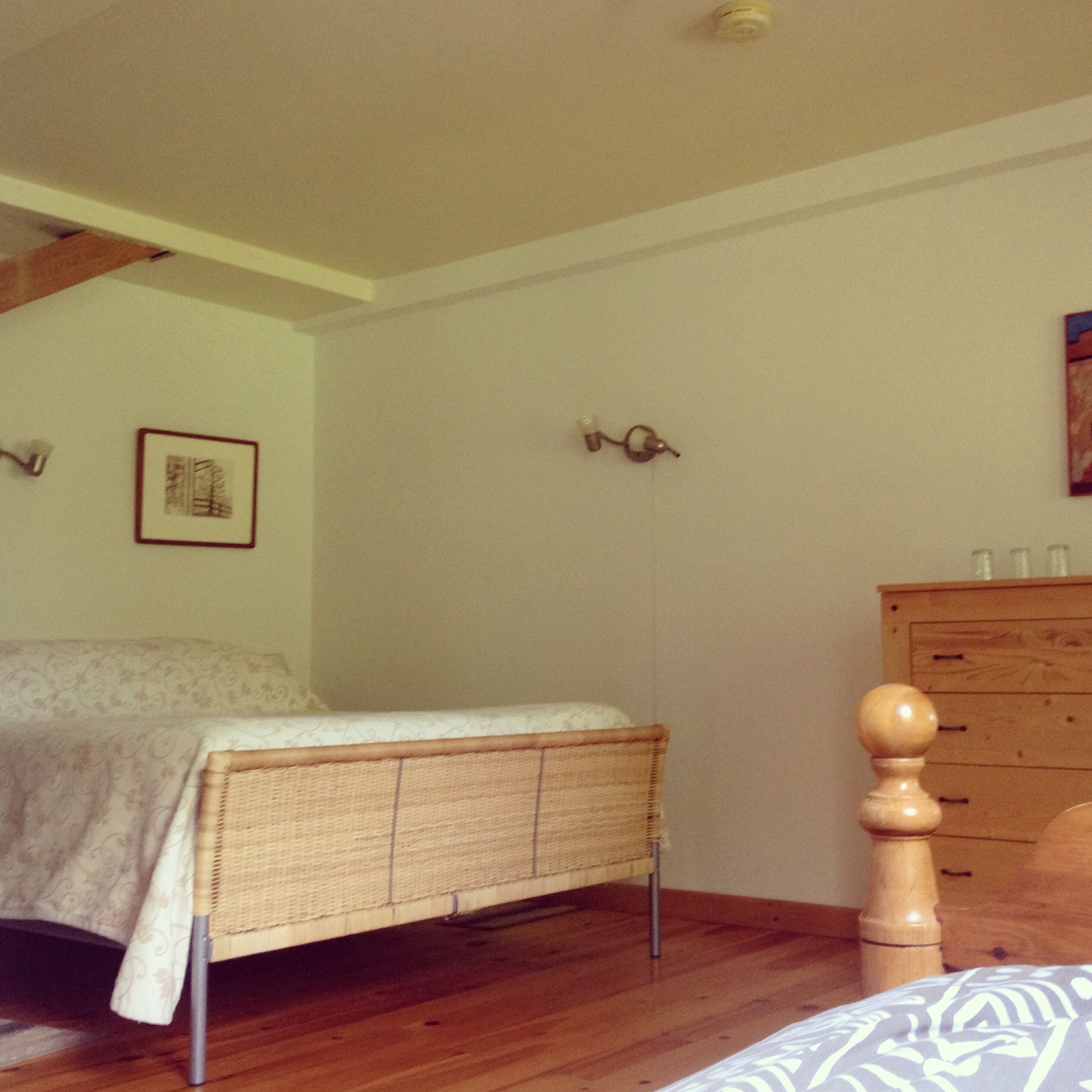 A bedroom with a bed, dresser, and a wall-mounted light fixture.