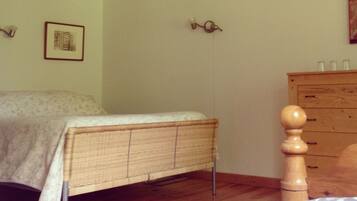 A bedroom with a bed, dresser, and a wall-mounted light fixture.