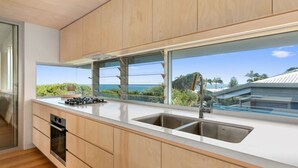 A modern kitchen with wooden cabinets, a stainless steel sink, and a gas stove. - Seaview Tce - Spectacular Home with Stunning Ocean and Headland Views (SUNSHINE BEACH)