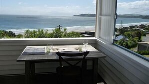 Un balcon avec une table et des chaises, donnant sur une plage et l’océan.
