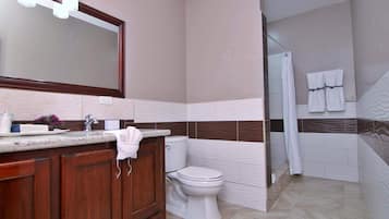 A modern bathroom with a large mirror, a sink with a towel, a toilet, and a shower area.