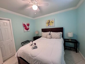 Ein Schlafzimmer mit einem Bett, zwei Nachttischen, einem Deckenventilator und Kunstwerken an den Wänden.