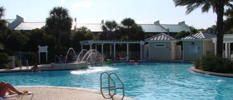 A swimming pool with lounge chairs and a water feature.