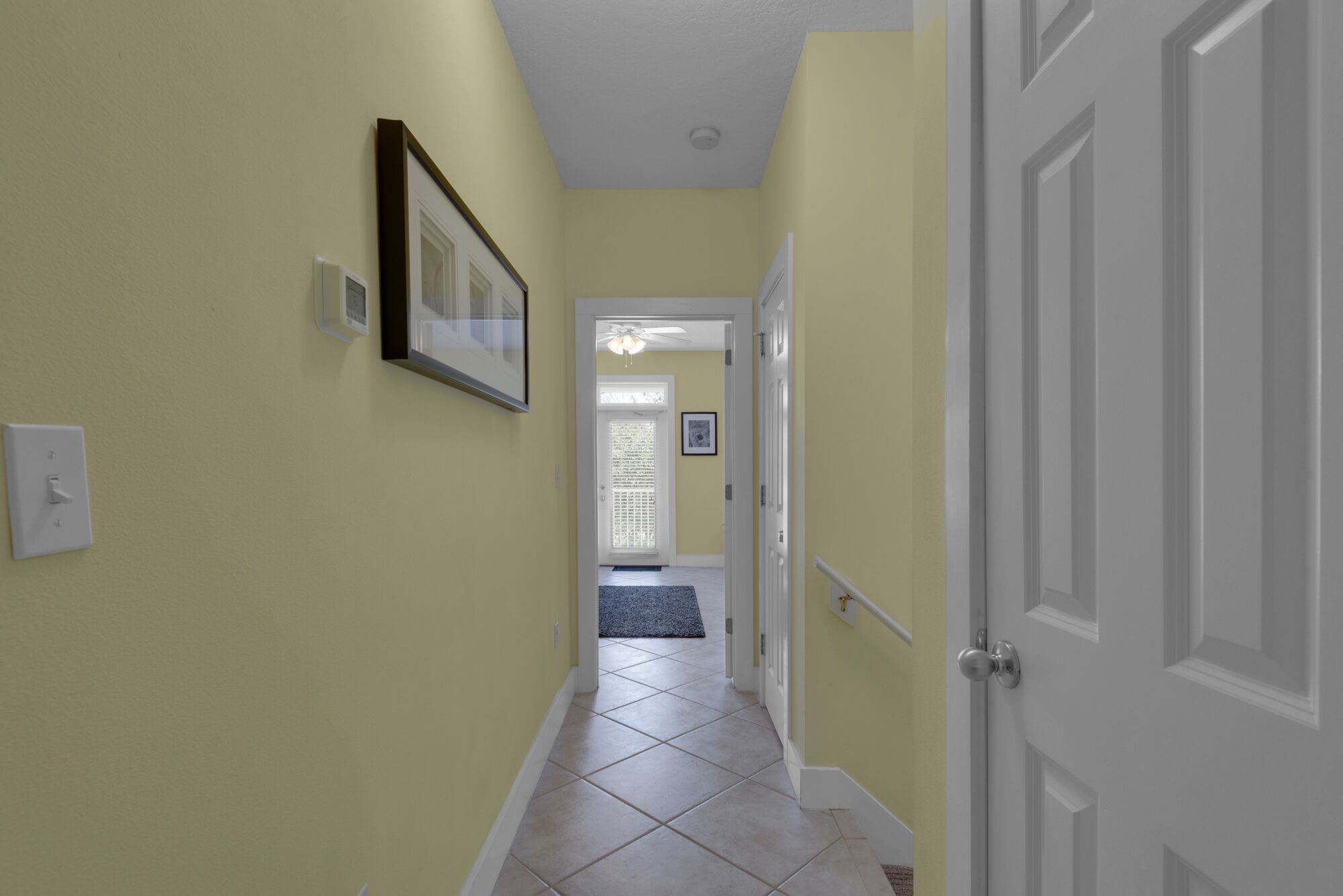 A hallway with yellow walls, white doors, and a tiled floor.
