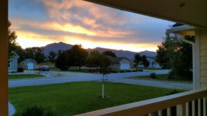Une rue résidentielle bordée de maisons, avec un ciel dégagé et des montagnes en arrière-plan.