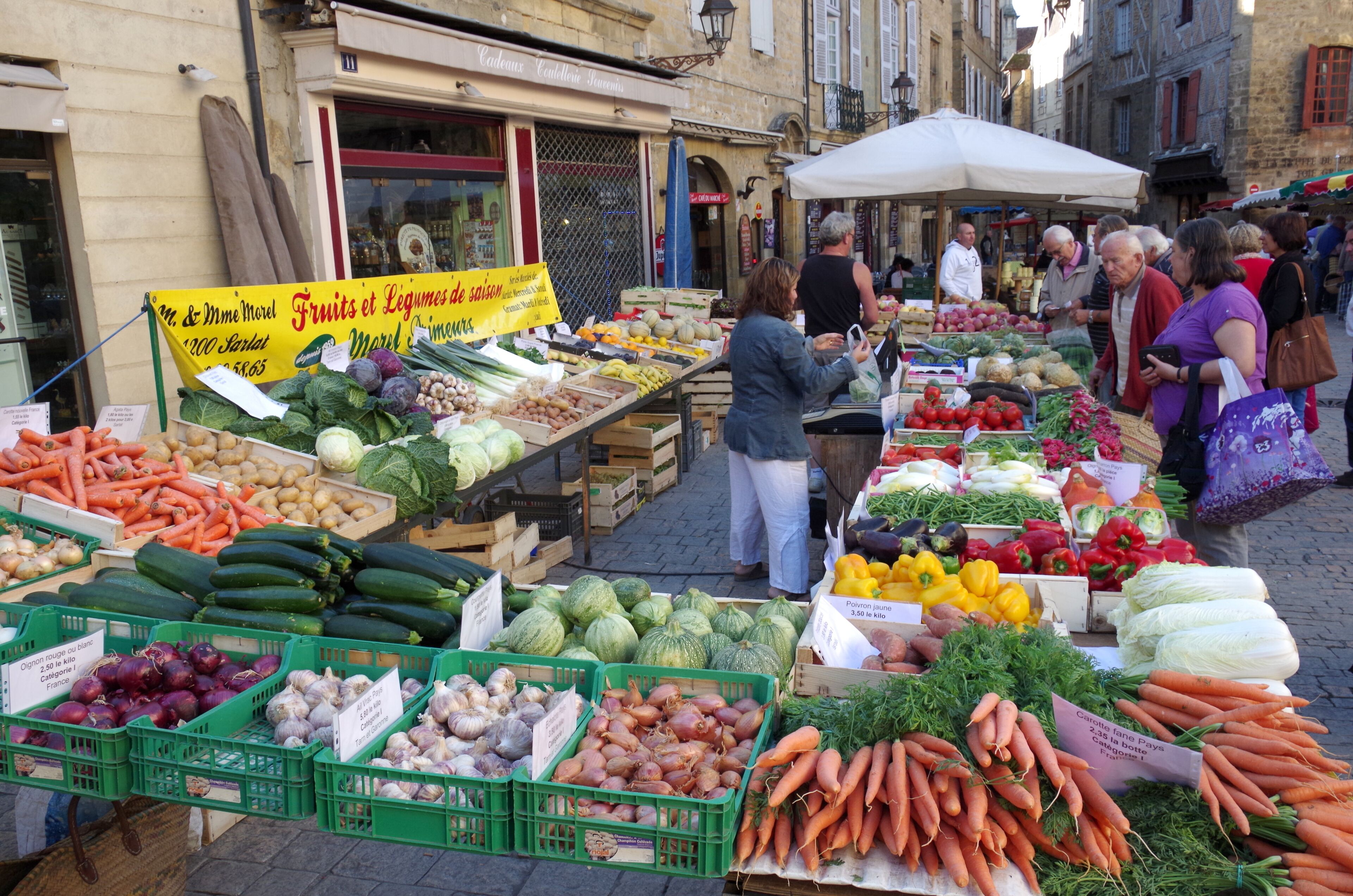 An outdoor market with various fresh produce displayed in crates and baskets.