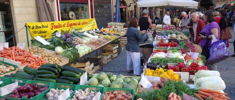 An outdoor market with various fresh produce displayed in crates and baskets.