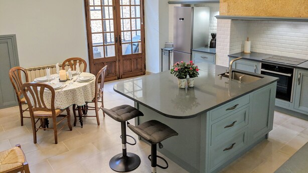 Una cocina con una isla central, sillas de madera, una mesa de comedor y un ventanal con vistas.