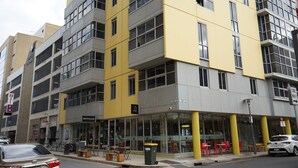 Een meerlaags gebouw met een café op de begane grond en terrasplekken.