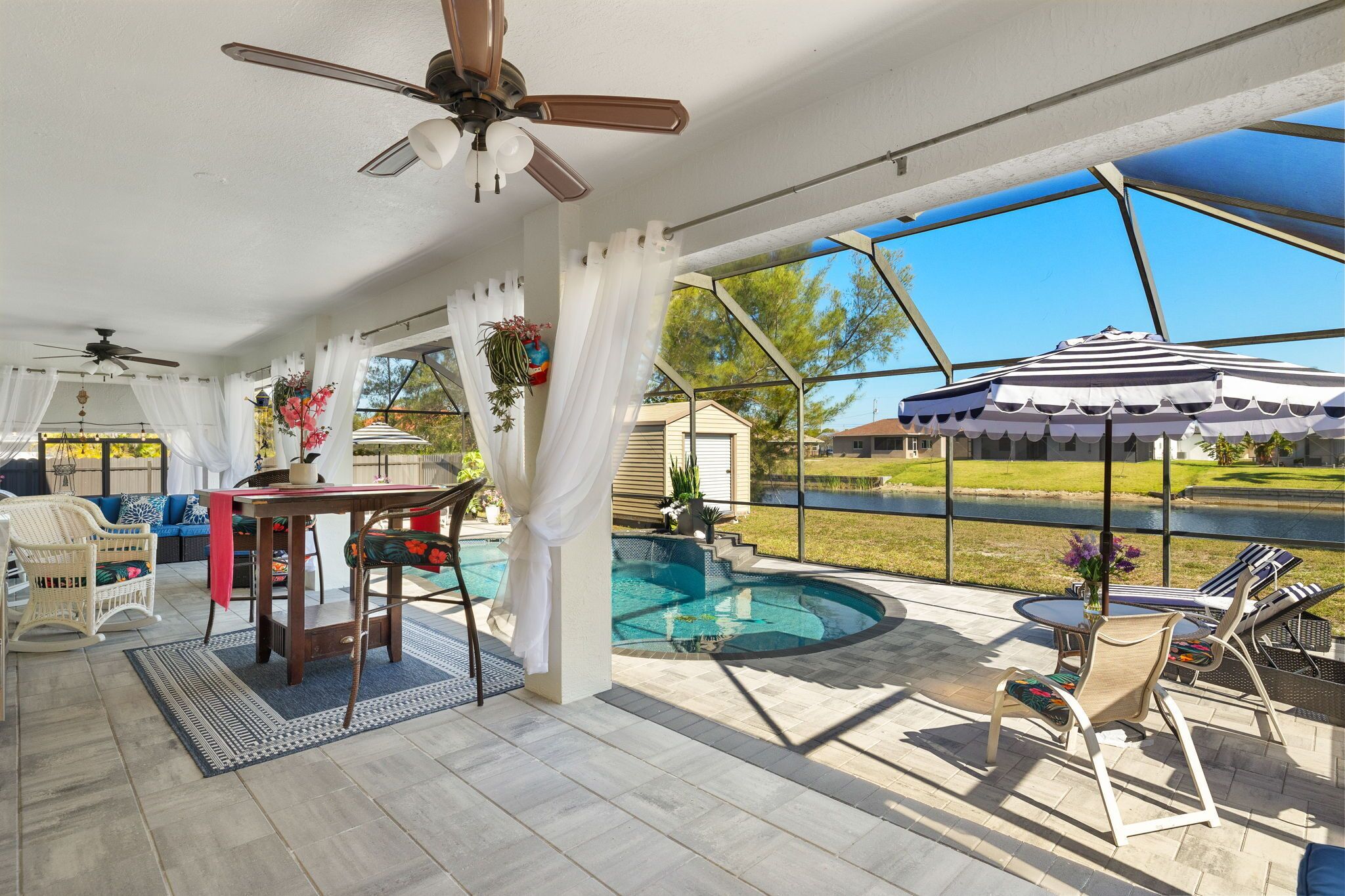 Un patio couvert avec une piscine, du mobilier d’extérieur et une vue sur une maison et un paysage.