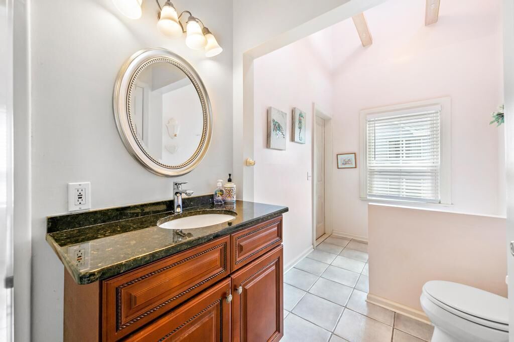 A bathroom with a vanity, sink, mirror, and toilet.