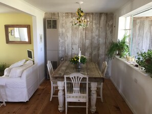 A dining area with a wooden table and chairs, a chandelier, and potted plants.