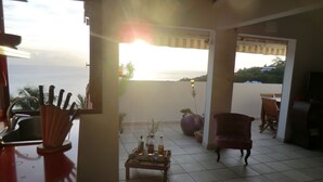 A living area with a view of the sea, a dining table with chairs, and a red sofa. - Exceptional Seaview - All The Comforts You Need (Schoelcher)