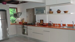 A modern kitchen with white cabinets, a stainless steel refrigerator, a microwave, and a sink. - Exceptional Seaview - All The Comforts You Need (Schoelcher)