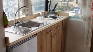 A compact kitchen with a sink, stove, and wooden cabinets.