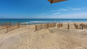 Ein Strand mit Holzzaun, blauem Himmel und ruhiger See.
