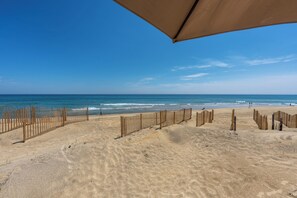 Ein Strand mit Holzzaun, blauem Himmel und ruhiger See.