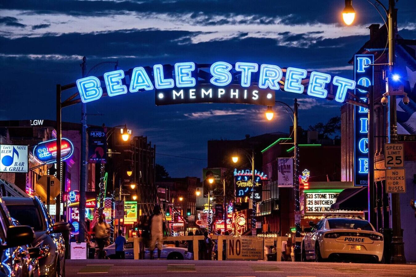 A busy street scene with neon signs, including "Beale Street Memphis" and "Police".