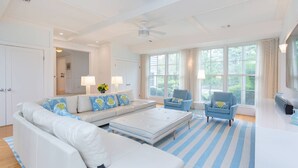 A spacious living room with a white sofa, blue armchairs, and a striped rug. - Stunning House: Tennis & Pool in Southampton Estate section (Southampton)