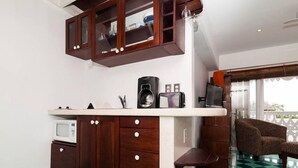 A compact kitchen with dark wooden cabinets, a microwave, a coffee maker, and a small countertop. - Plantation House - Ocean view - Family and pet friendly (Playa del Carmen)