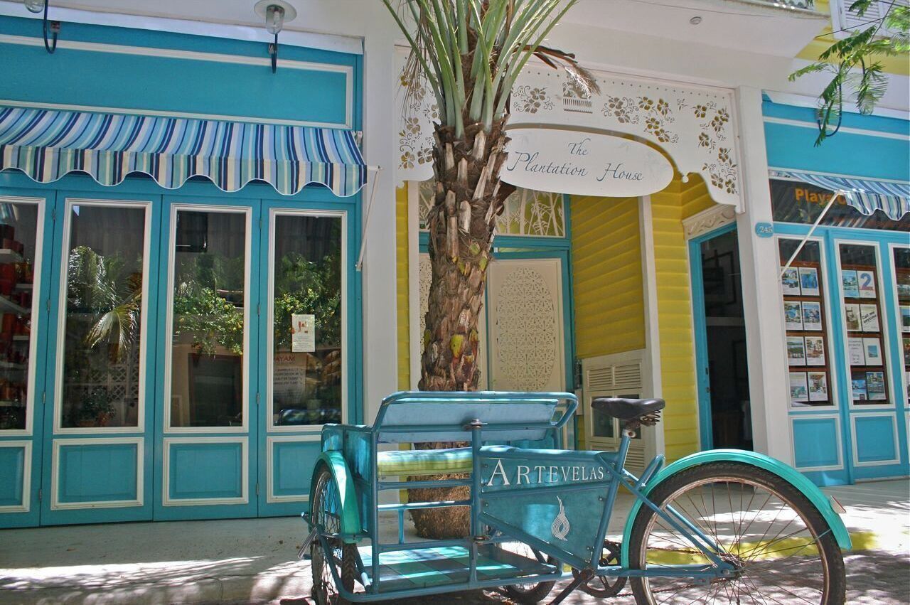 Un vélo turquoise est garé devant un bâtiment sur lequel on peut lire l’inscription « The Plantation House ».