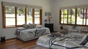 A bedroom with two beds, large windows, a small desk, and a chair. - Shizunami Retreat Bermagui (Bermagui)
