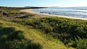 A coastal landscape with a beach, grassy areas, and a clear sky. - Shizunami Retreat Bermagui (Bermagui)