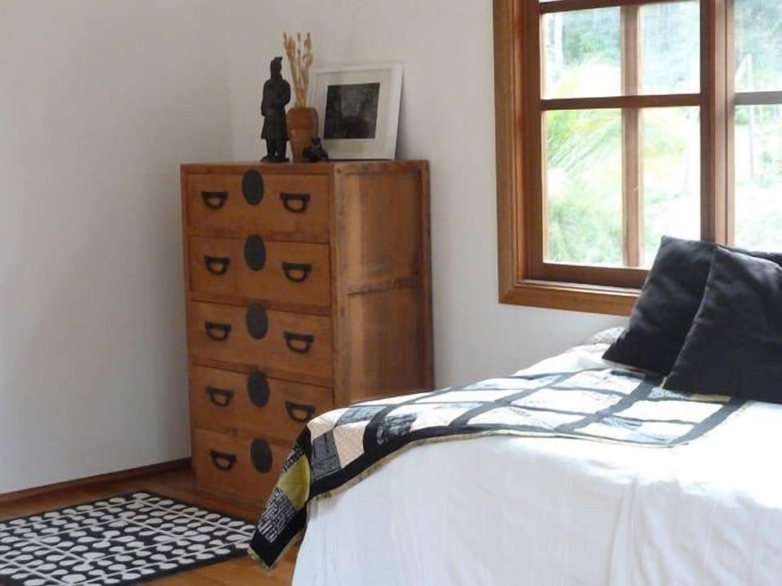 Een slaapkamer met een bed, een kaptafel, een raam en een vloerkleed.