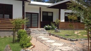A modern house with a stone pathway leading to the entrance, surrounded by small trees and a well-maintained lawn. - Shizunami Retreat Bermagui (Bermagui)
