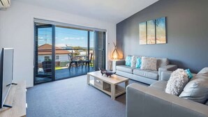 A modern living room with a sofa, coffee table, and artwork on the wall. - Unit 3 - Modern 2BR Apartment on Huskisson Main Street By Nautilus Apartments Je (Huskisson)