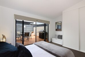 Relax in this stylish room with a large bed, bedside table, and sliding glass door leading to a balcony with a table and chairs.