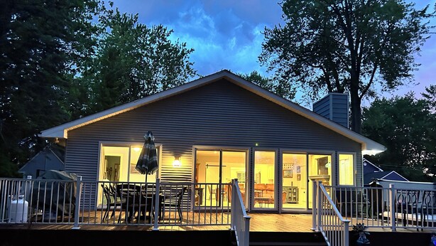 A house with a covered patio, a fenced deck, and a staircase leading to the entrance.