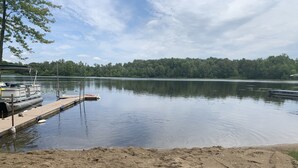 A calm lake with a dock and boats, surrounded by trees and a clear sky.