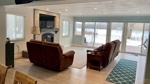 A living room with a fireplace, large windows, and a view of a snowy landscape.