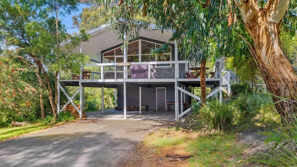 A modern house with a covered outdoor area and a staircase leading to a deck.