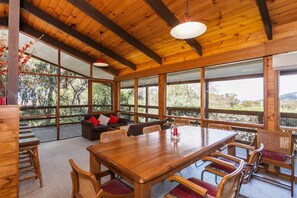 A wooden interior with a large dining table, chairs, and a sofa with cushions. - La Tienda (Lorne)