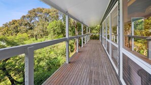 A wooden deck with a white railing, overlooking a forested area. - La Tienda (Lorne)