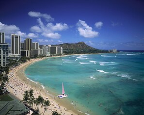 A coastal cityscape with a beach, high-rise buildings, and a clear sky.