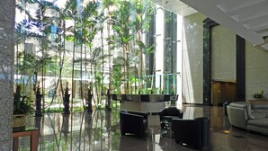 En moderne lobby med glasvæg, indendørs planter og siddeområder.