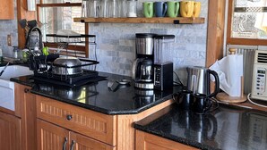 Une cuisine avec des meubles en bois, un plan de travail noir et divers appareils de cuisine.