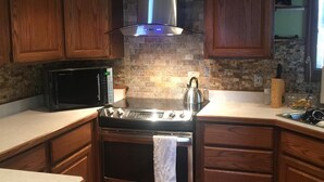 Una cocina compacta con gabinetes de madera, una estufa de acero inoxidable y un microondas.