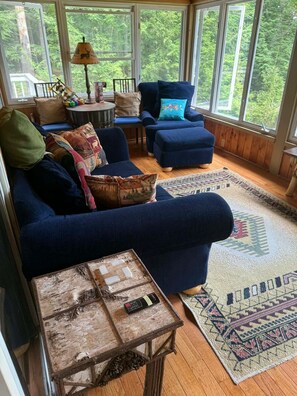 A cozy living room with a blue sofa, a patterned rug, and a rustic coffee table.