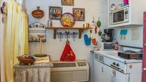 Een compacte keuken met een retro magnetron, een kleine koelkast en een raam boven de gootsteen.
