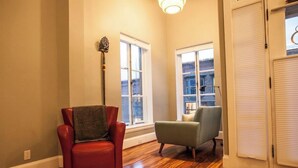 Um quarto com uma poltrona vermelha, uma poltrona verde e um abajur alto.