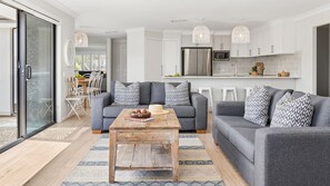 A modern living room with grey sofas, a wooden coffee table, and patterned cushions.