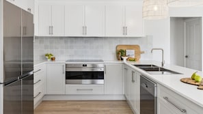 A modern kitchen with white cabinets, stainless steel appliances, and a wooden countertop.