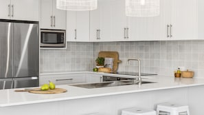 A modern kitchen with stainless steel appliances, a central island, and a tiled backsplash.