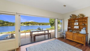 Une pièce avec un banc en bois, une petite table, une bibliothèque et une vue sur un lac.