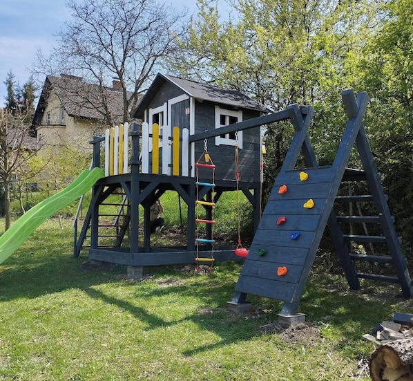 Een speeltuin met een glijbaan, klimmuur en schommelzeth.